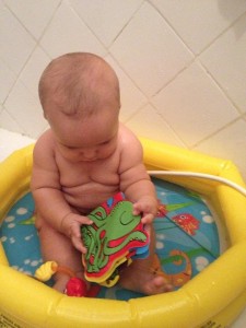 Tomando banho na piscininha brincando com o livrinho de plástico do polvo